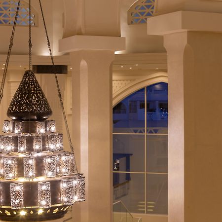 Pickalbatros Palace Sharm - "Aqua Park" Esterno foto The photo shows a beautifully designed chandelier hanging from the ceiling of a spacious interior. The chandelier features a structure with multiple levels and includes ornate patterns, likely made of metal or glass, that diffuse light elegantly. The