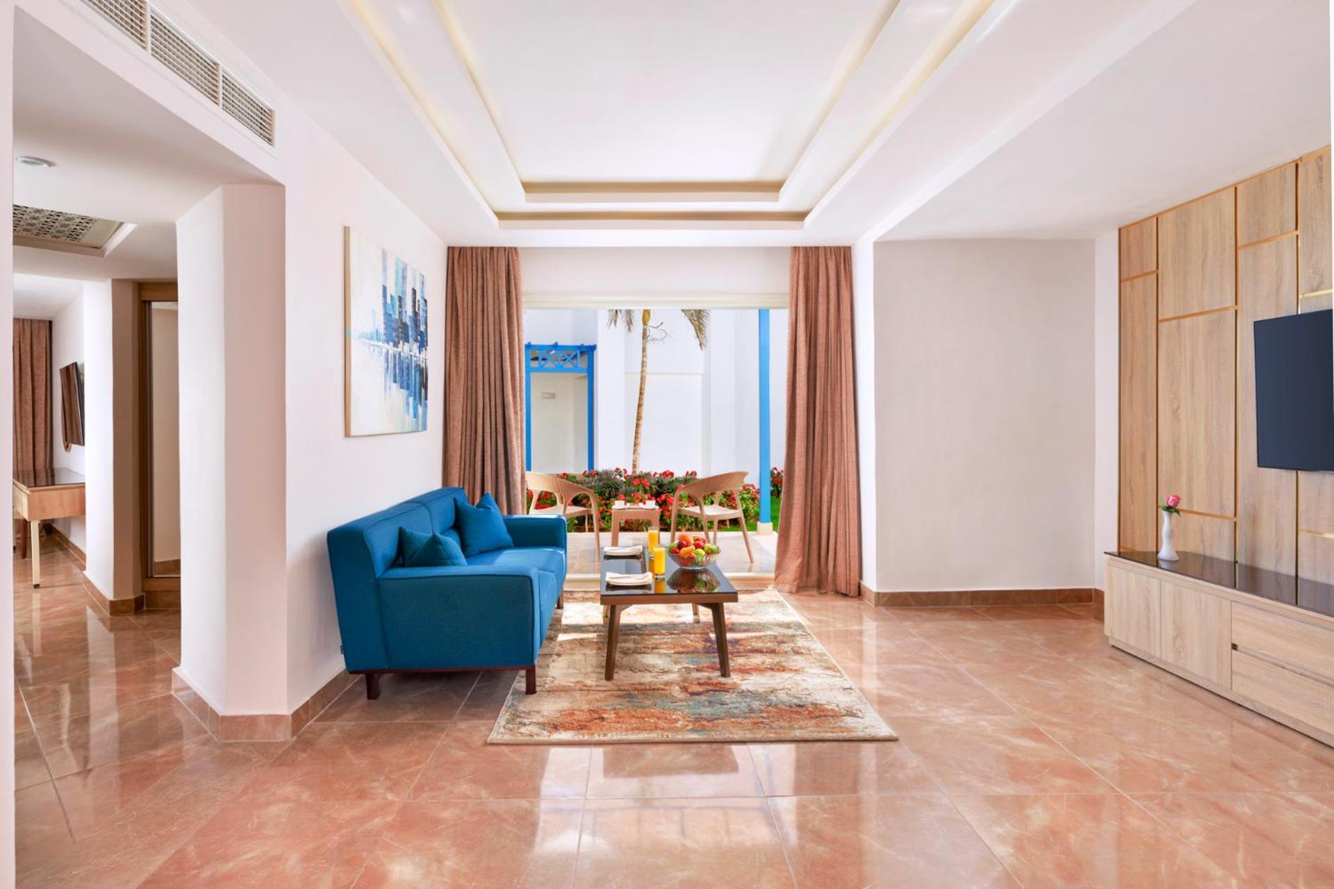 Pickalbatros Palace Sharm - "Aqua Park" Esterno foto The photo shows a modern living room decorated with a bright and inviting style. In the center, there is a cozy blue sofa positioned against a wall. A coffee table sits in front of the sofa, accompanied by a decorative rug underneath. The room featur